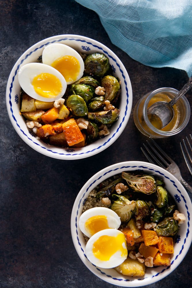 Overhead view of a grain bowl topped with roasted butternut, Brussels sprouts, and a jammy egg and drizzles with brown butter. 