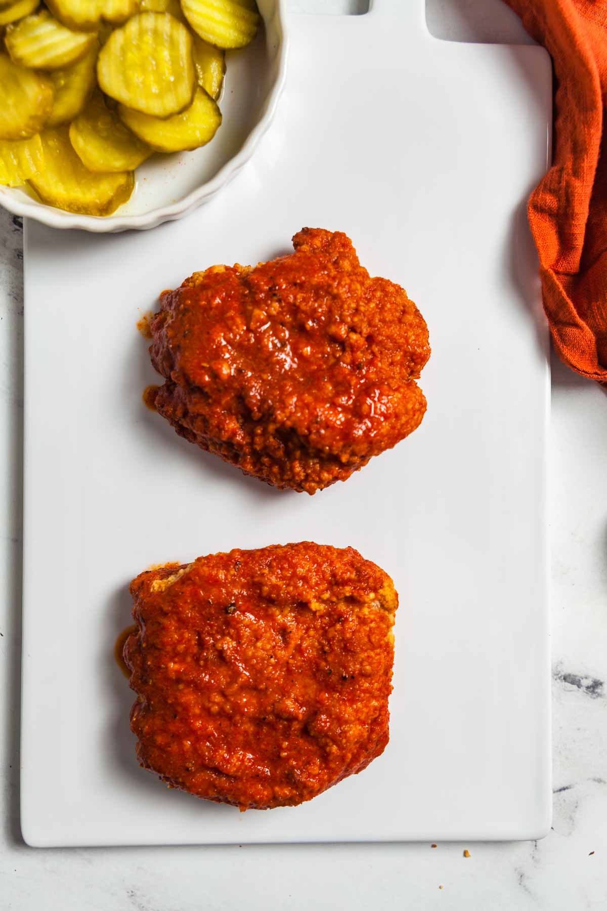 Two air fryer chicken breasts coats with Nashville hot sauce. 