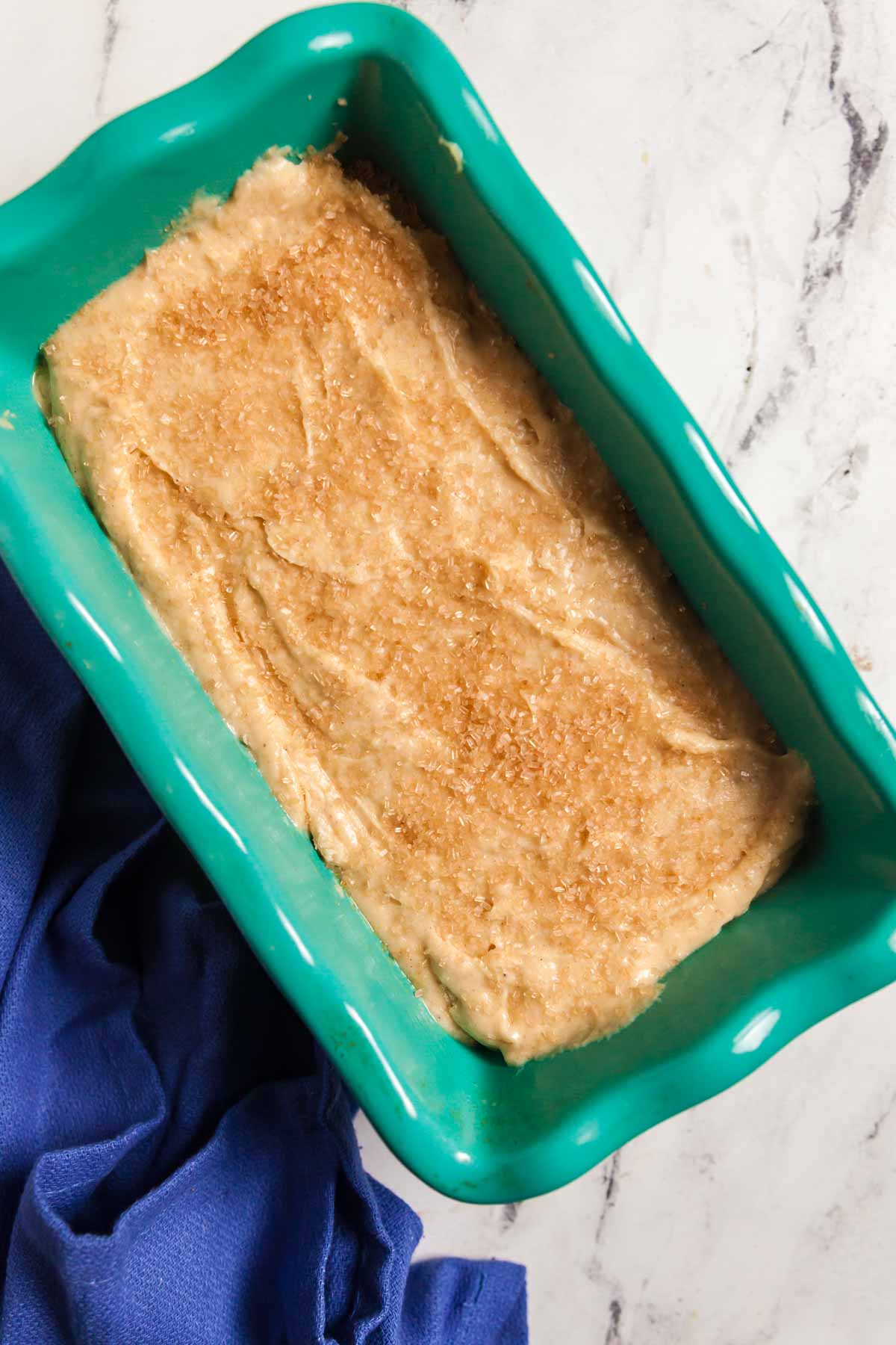 A teal loaf pan filled with quick bread batter. 