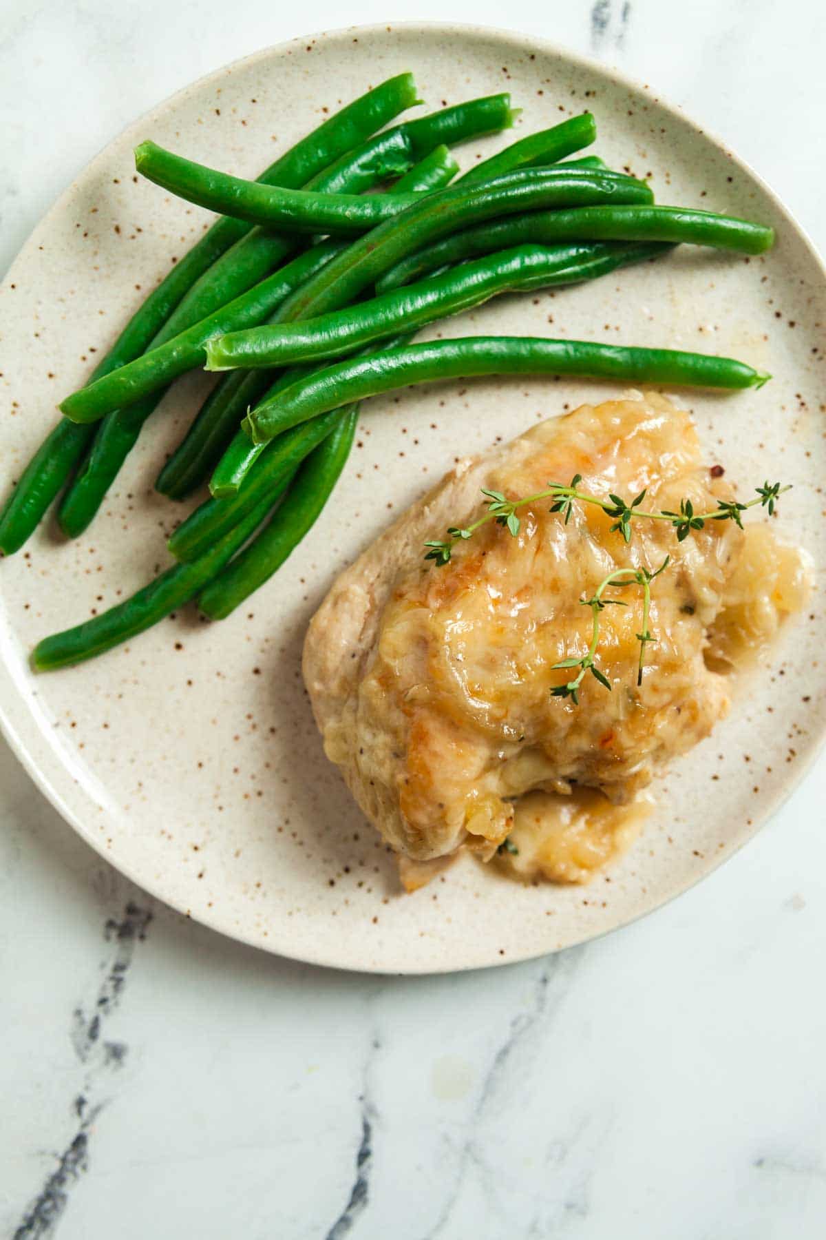 A plate with skillet French onion chicken and green beans.