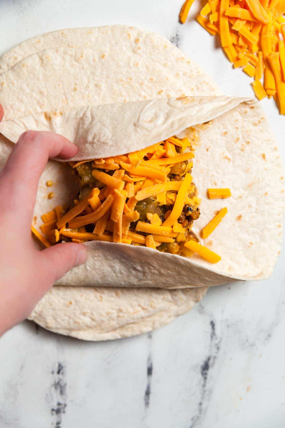 The process of wrapping green chile breakfast burritos.