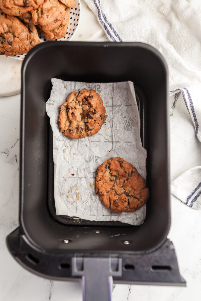 Overhead vie of chocolate chip cookies cooling in a Ninja foodi air fryer basket. 