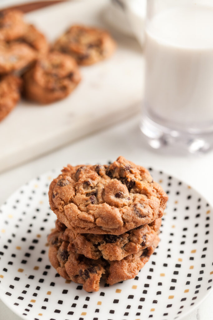 3 stacked air fryer cookies on a plate with a glass of milk.