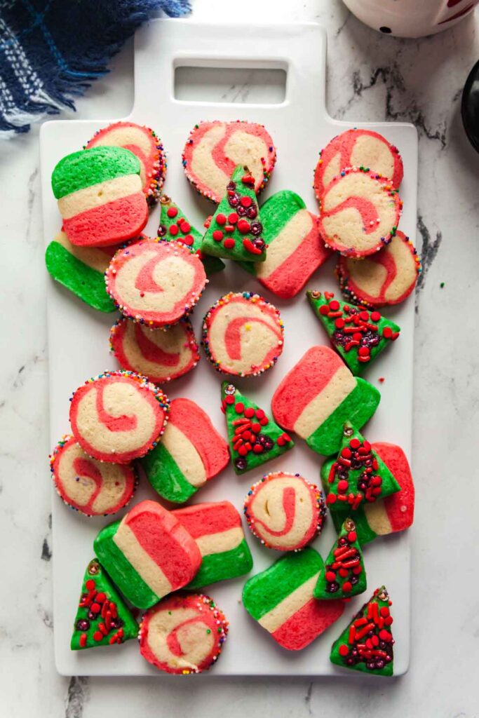 A white board piled with red, white, and green slice and bake sugar cookies. 