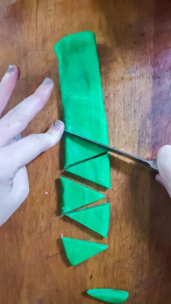 Cutting green cookie dough into triangles to make Christmas trees.