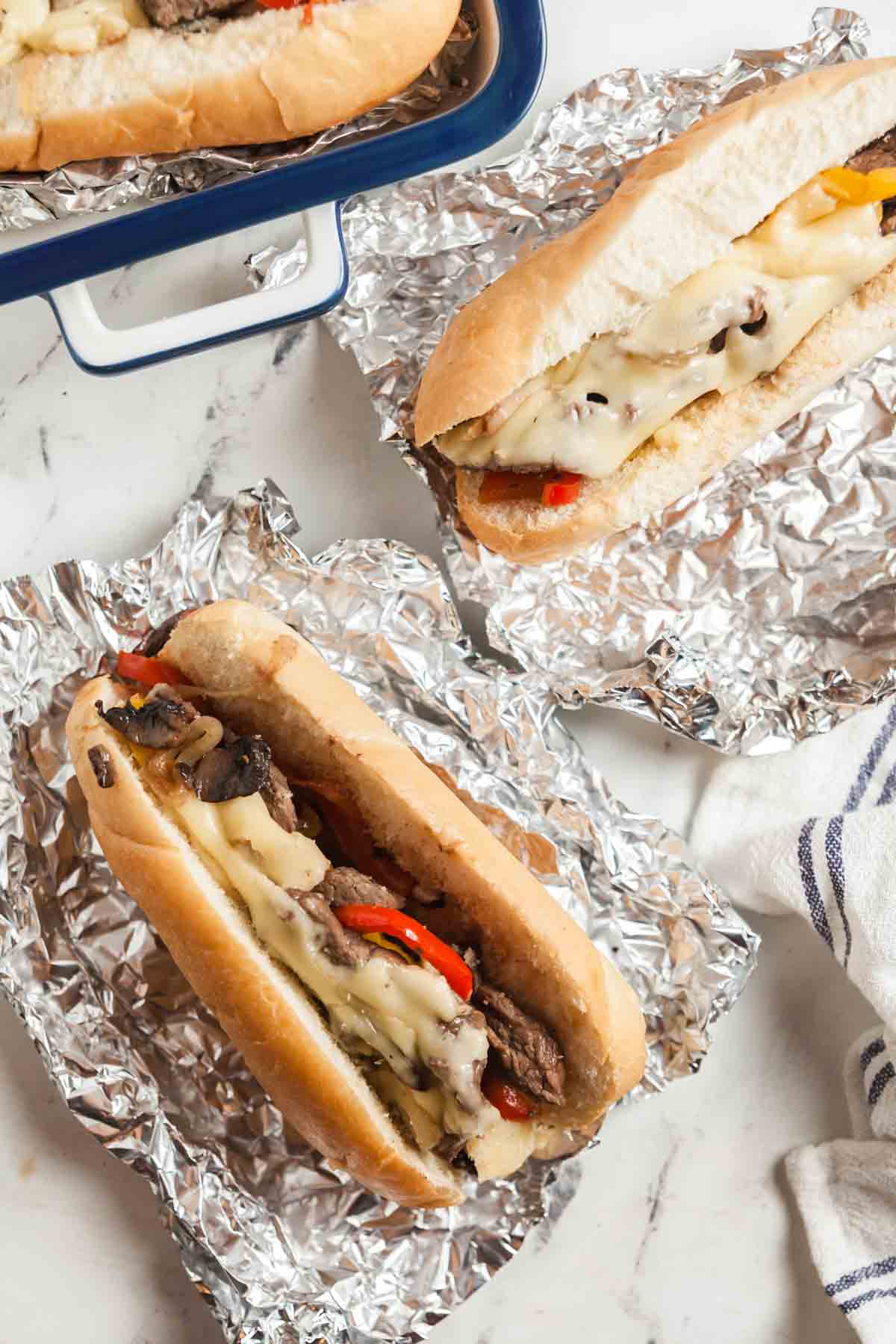 Cheesesteak sandwiches on foil.