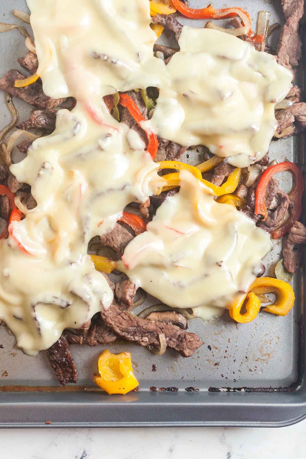 Melting the cheese on top of the Sheet pan cheesesteak filling