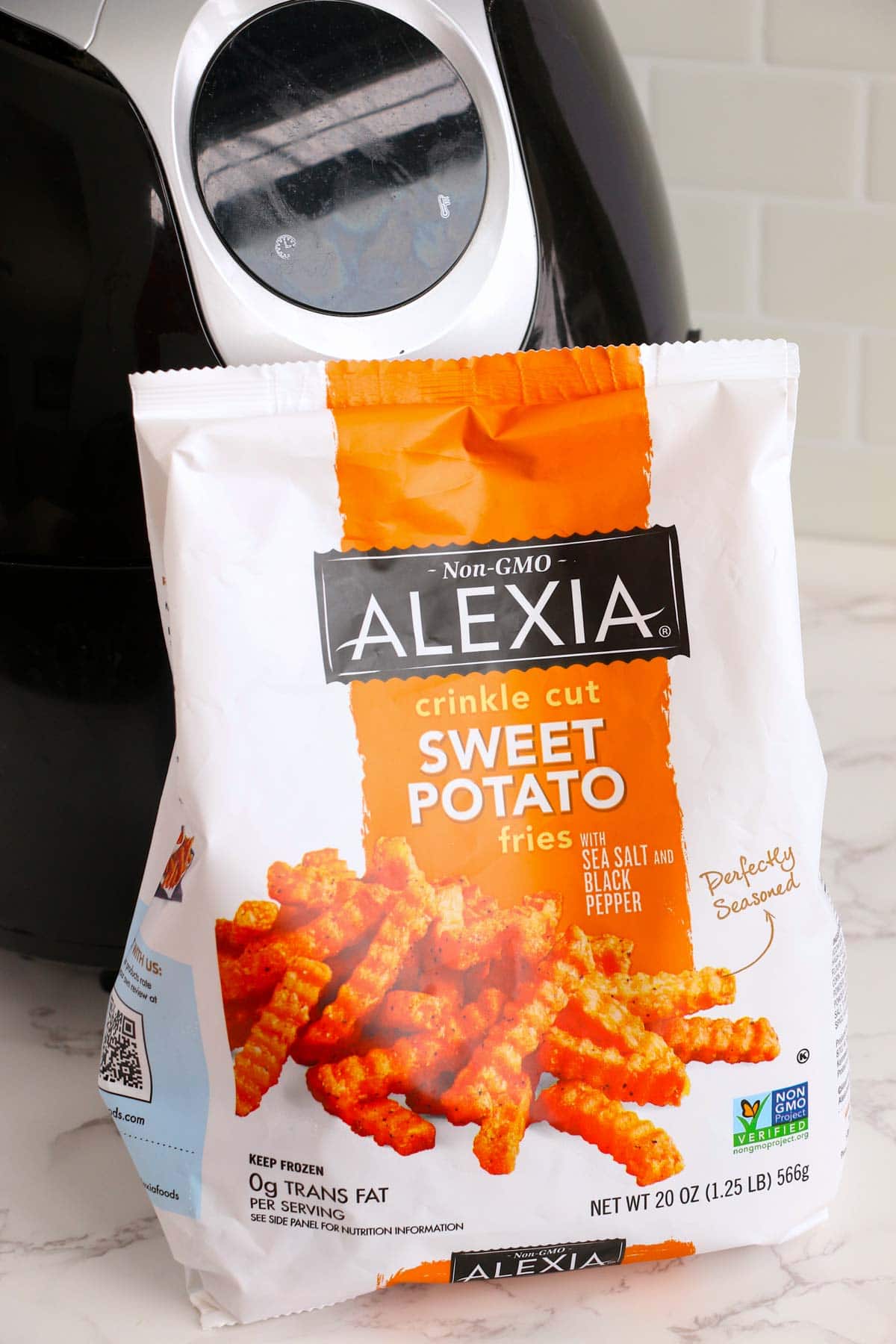 A bag of Alexia frozen sweet potato fries in front of an air fryer.