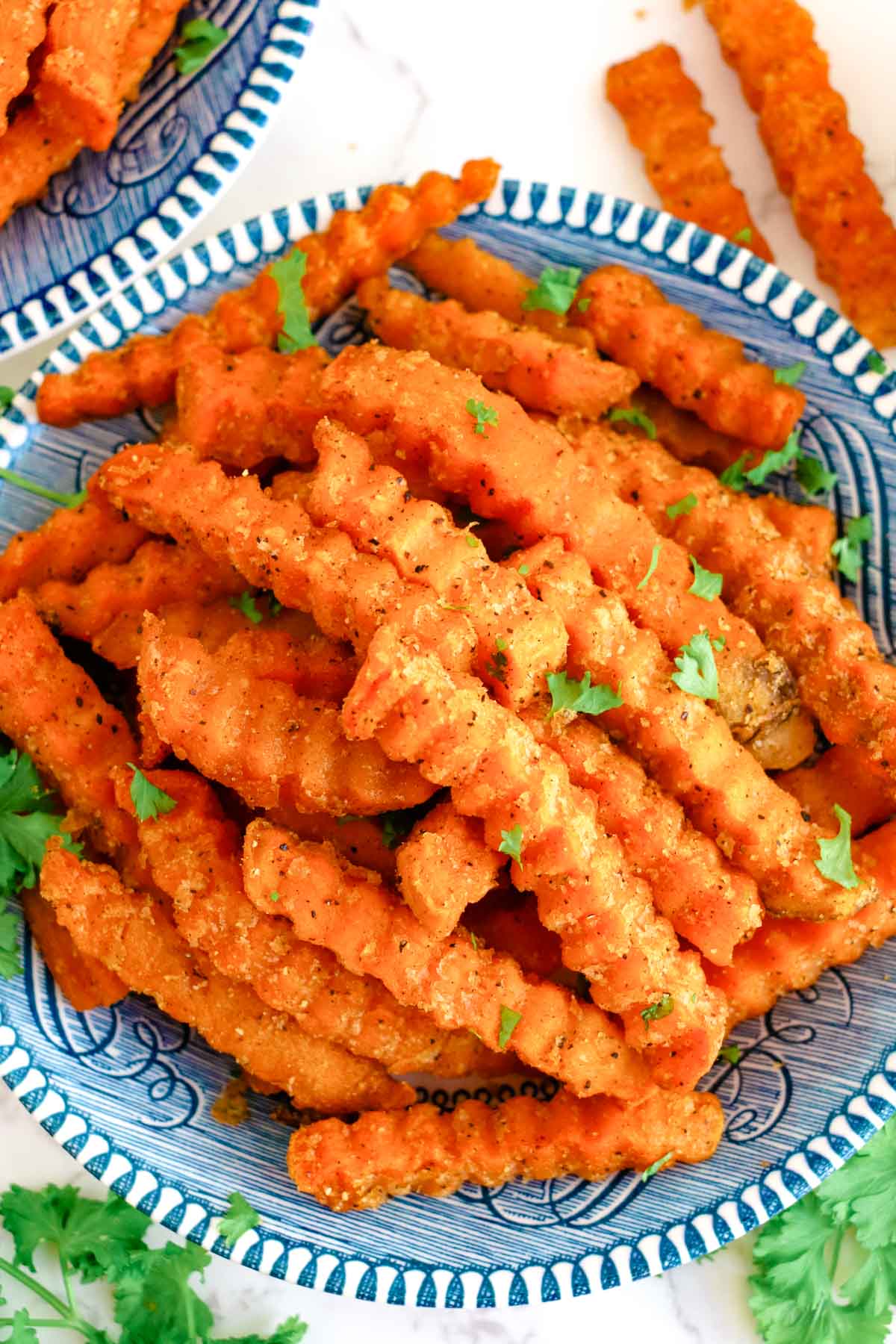 Overhead view of air fryer sweet potato fries on a blue plate.
