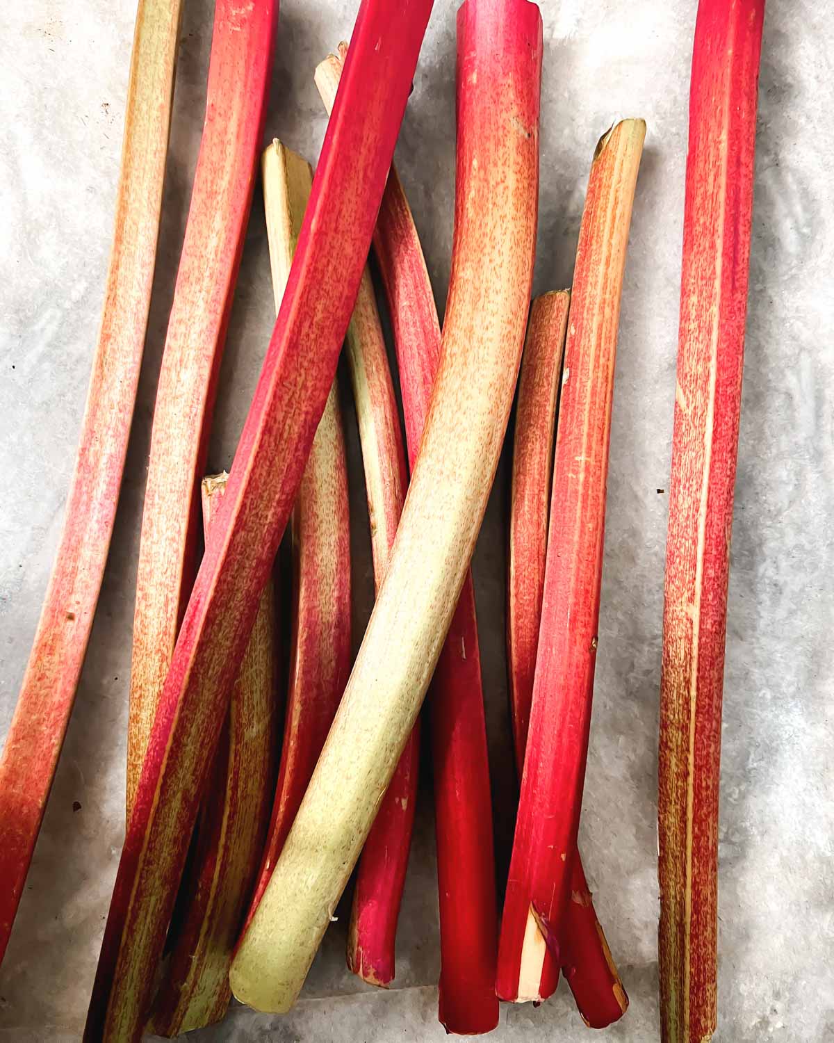 A pile of fresh rhubarb on a marble counter.
