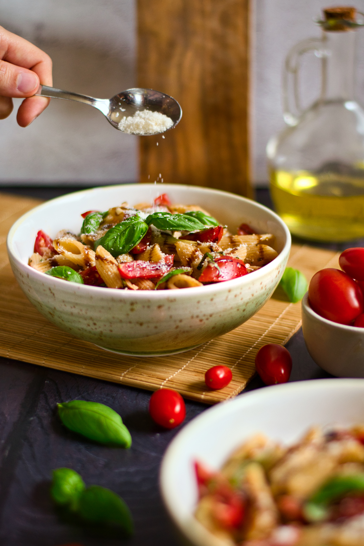 Sprinkling Parmesan cheese on a bowl of pasta with fresh tomato sauce. 