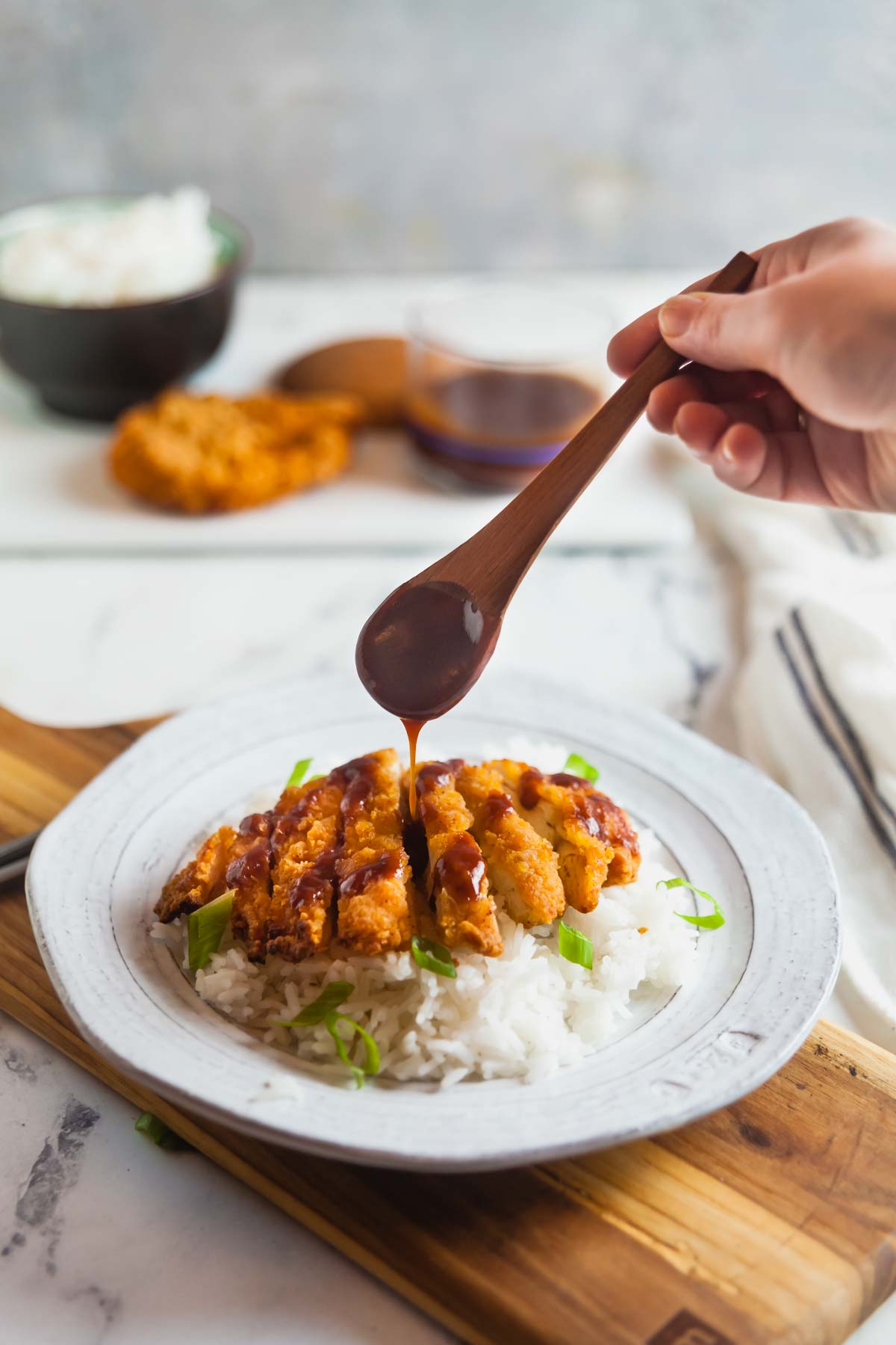 Drizzling katsu sauce over air fried chicken katsu