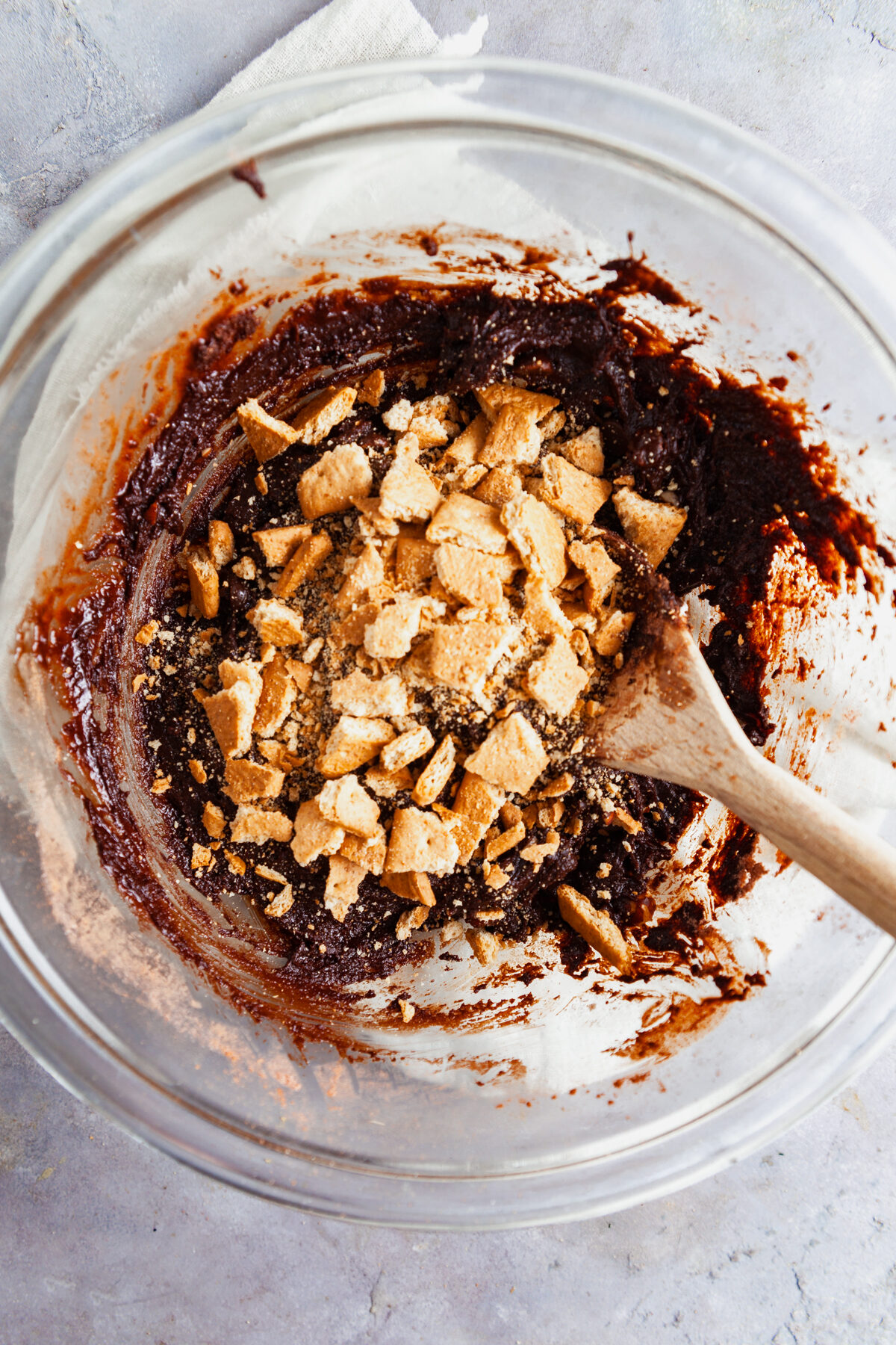 Stirring graham crackers into the dough to make s'mores cookies. 