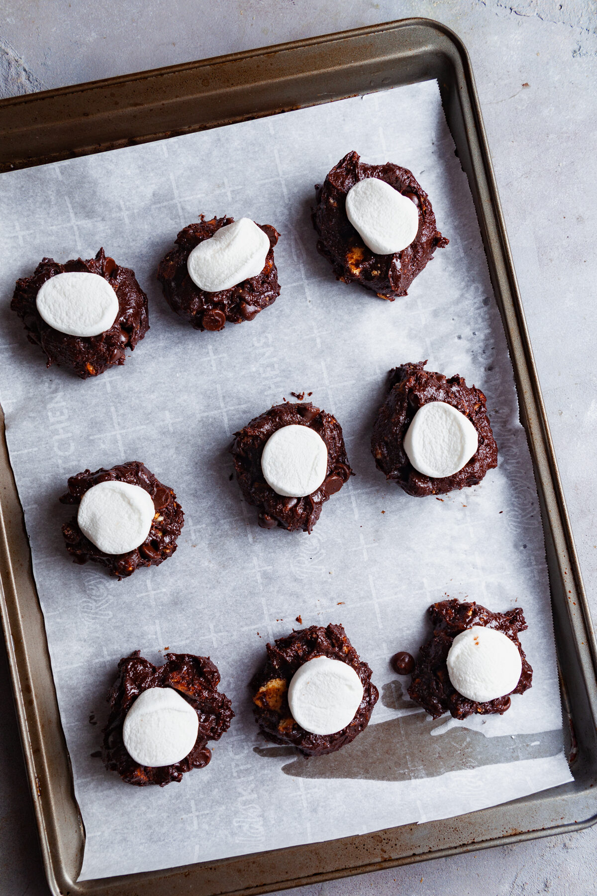 Topping each scooped brownie cookie with a marshmallow. 
