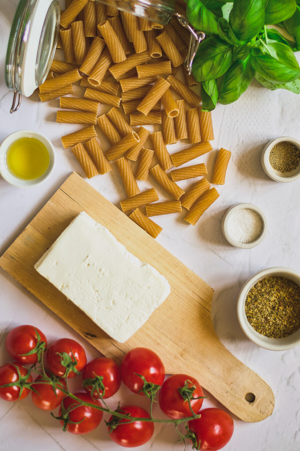 Ingredients needed to make feta pasta include block feta, cherry tomatoes, and fresh basil. 