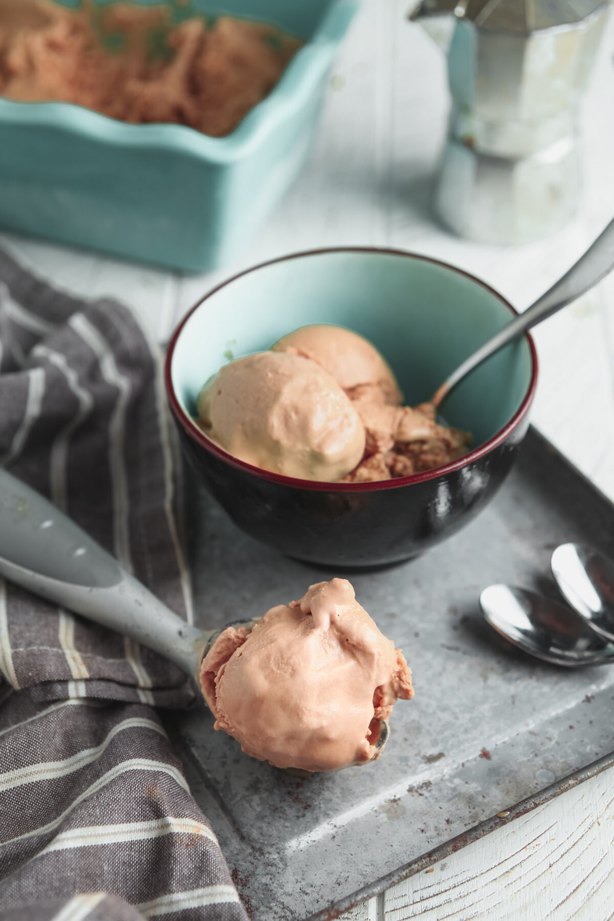 A scene with coffee ice cream on a grey tray and an espresso pot. 