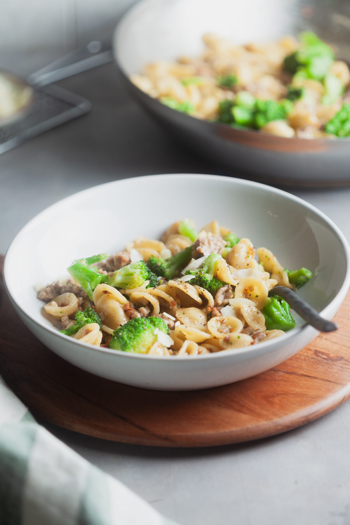 Serving two bowls on pasta with sausage and broccoli.