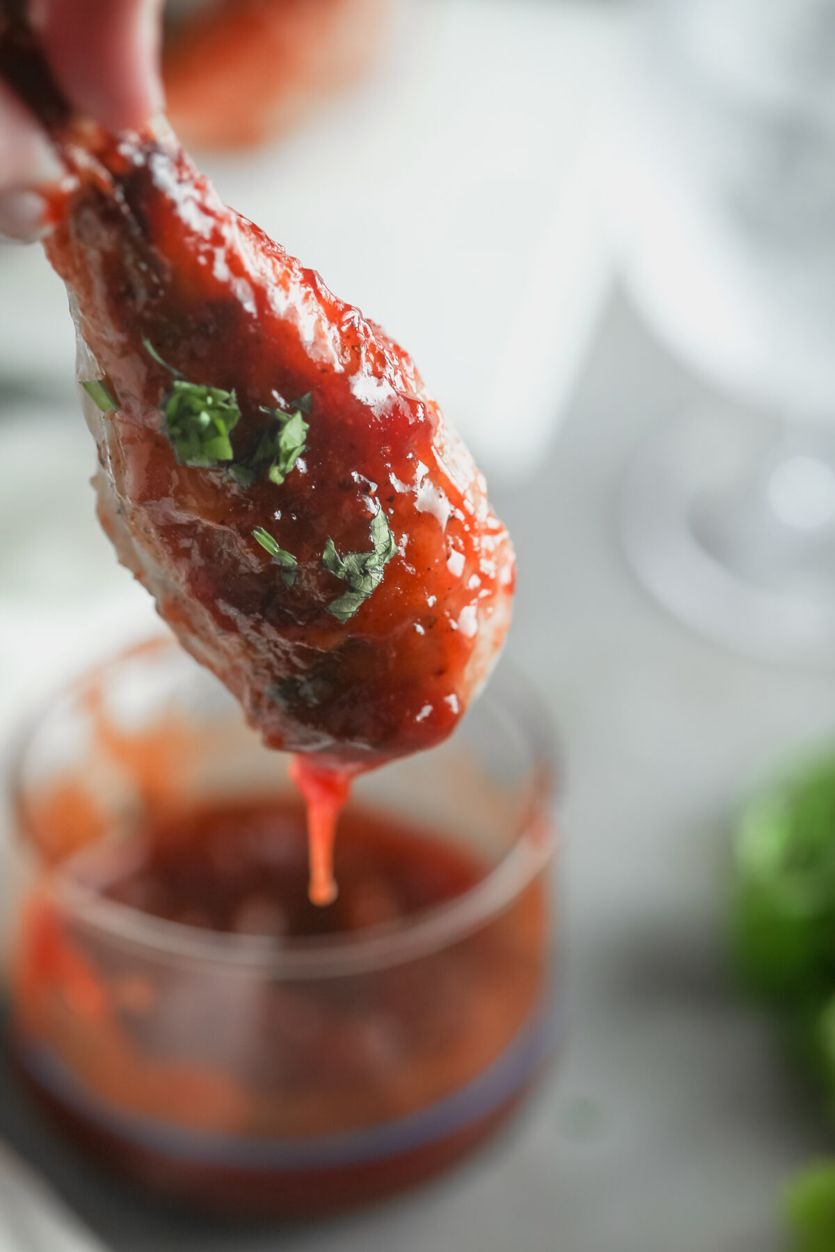 Dipping a chicken drumstick into BBQ sauce. 