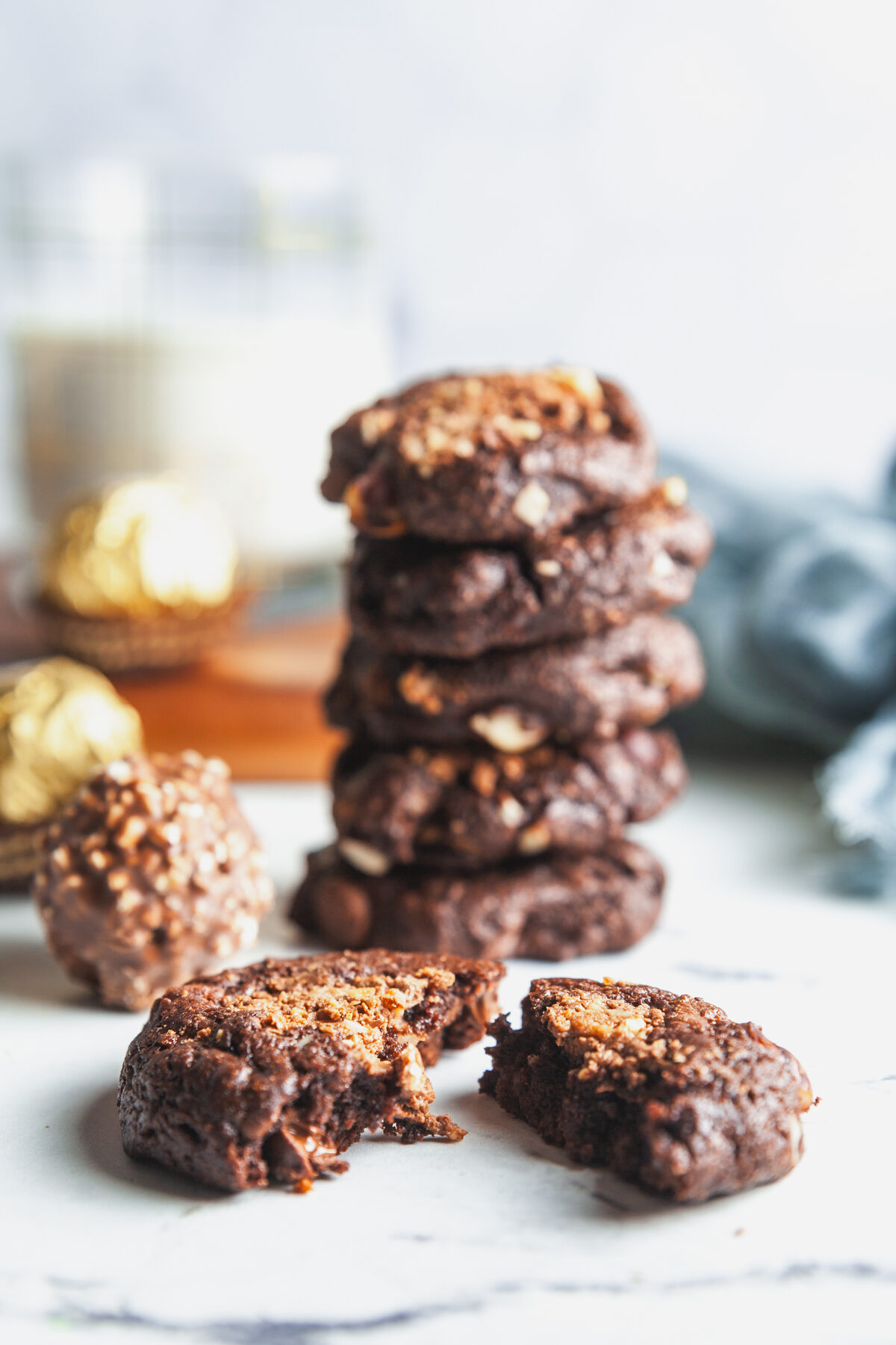 Stack of chocolate hazelnut cookies with a glass of milk and ferrero rocher candies.