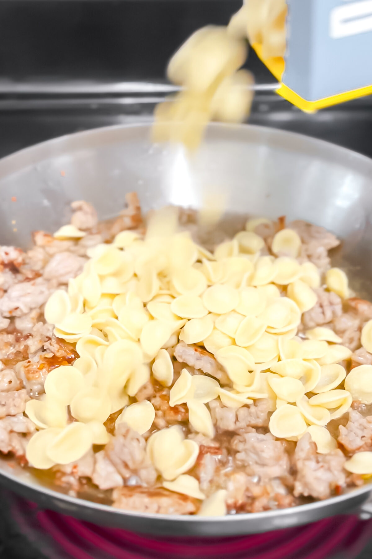 Pouring in the dry pasta.