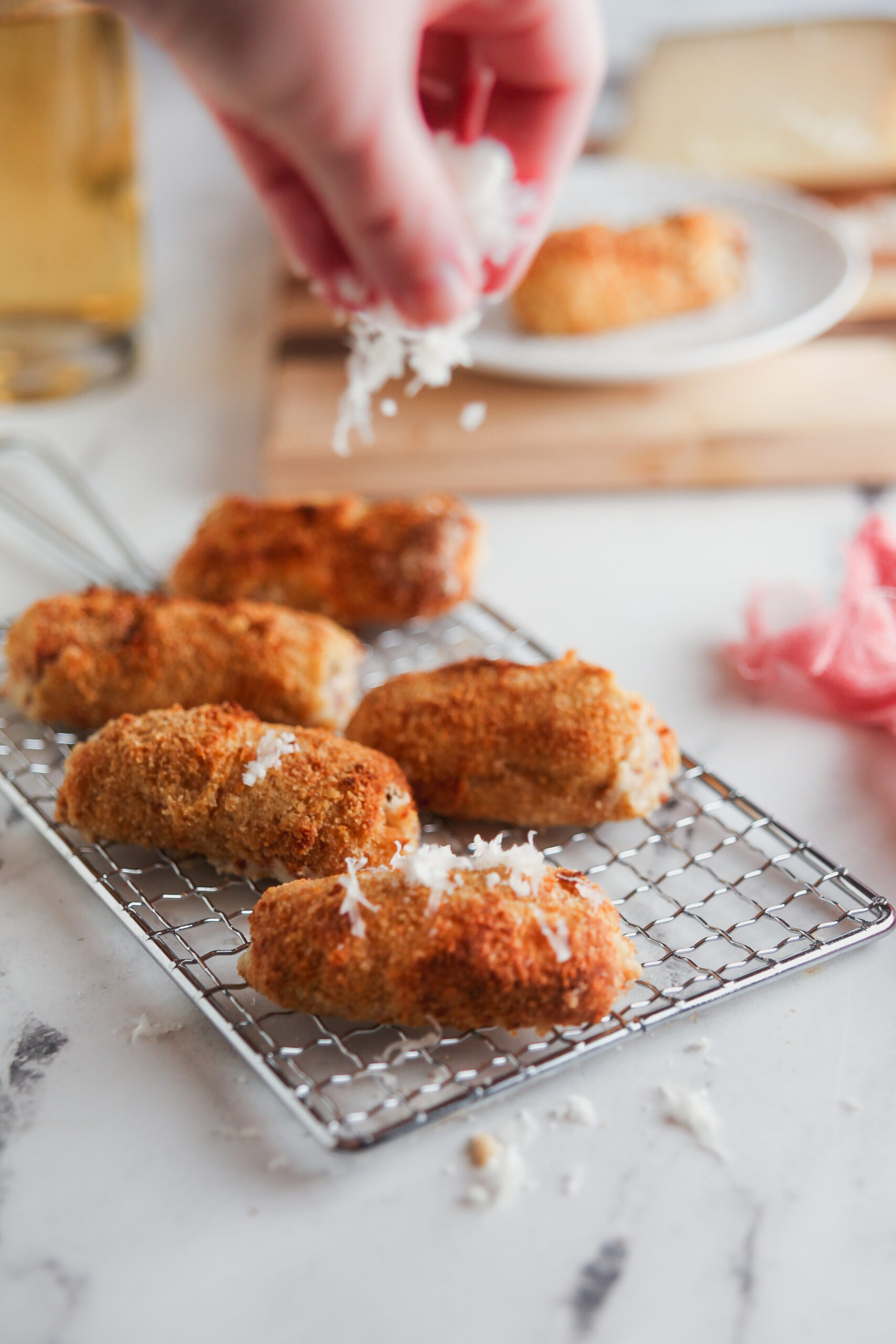 Sprinkling manchego cheese onto ham croquettes.