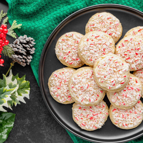 A plate of cake mix cookies with peppermint frosting and candy cane pieces.