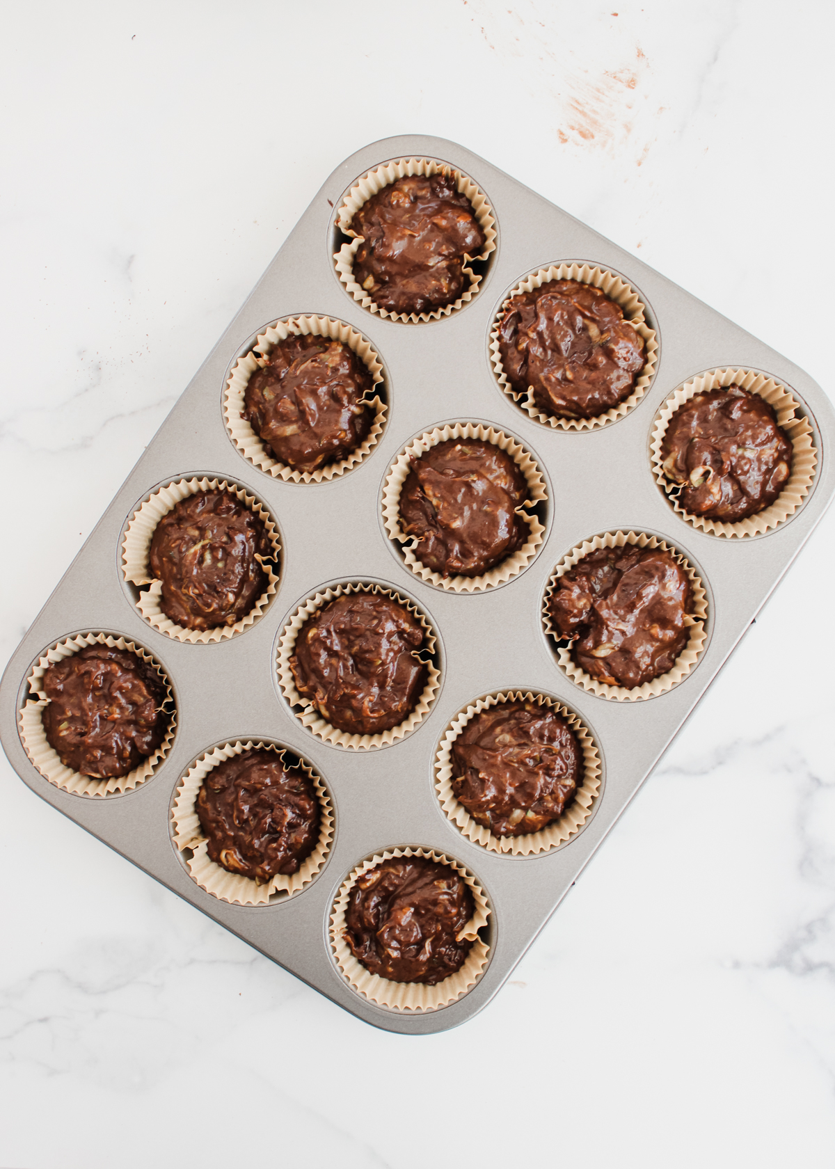 Scooping the zucchini muffin batter into a prepared tin. 