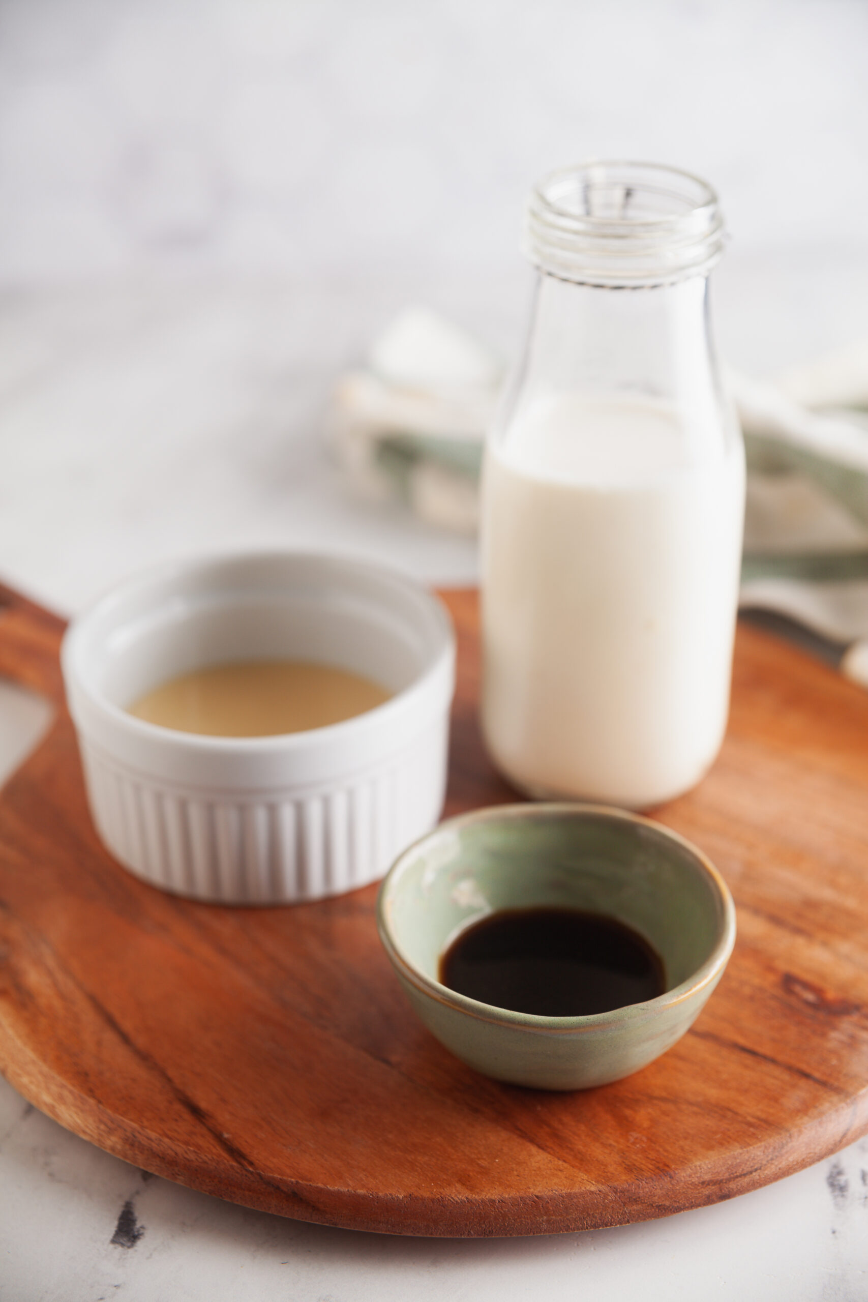 A wooden board with heavy cream, condensed milk, and vanilla ready to be turned into cold foam for coffee. 