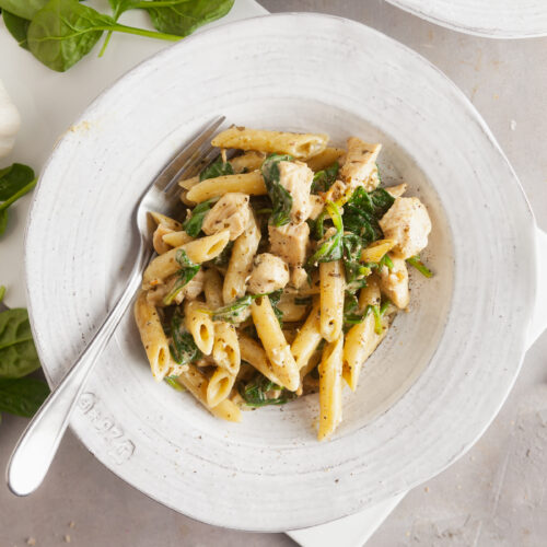 Creamy pesto pasta in a white bowl.