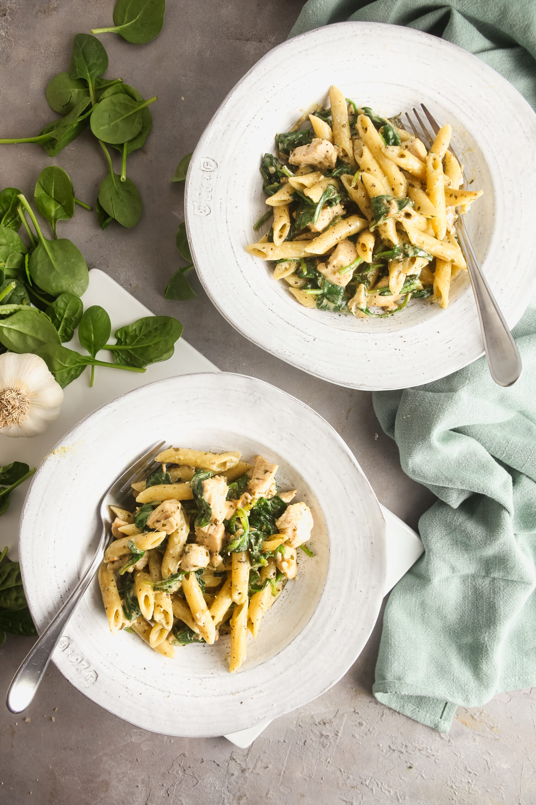 Two white bowls filled with creamy pesto chicken pasta. 