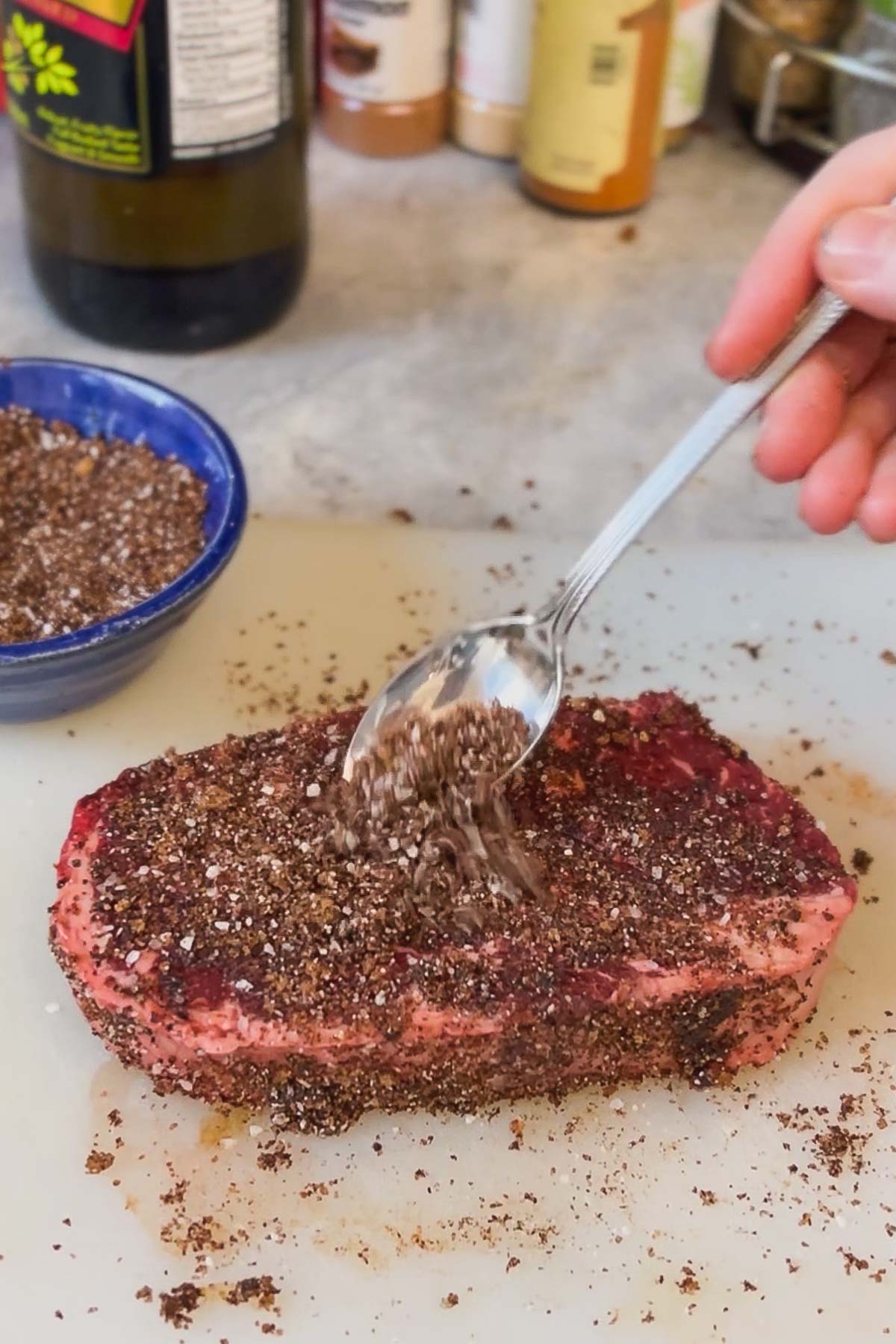 Spreading the rub onto steak.