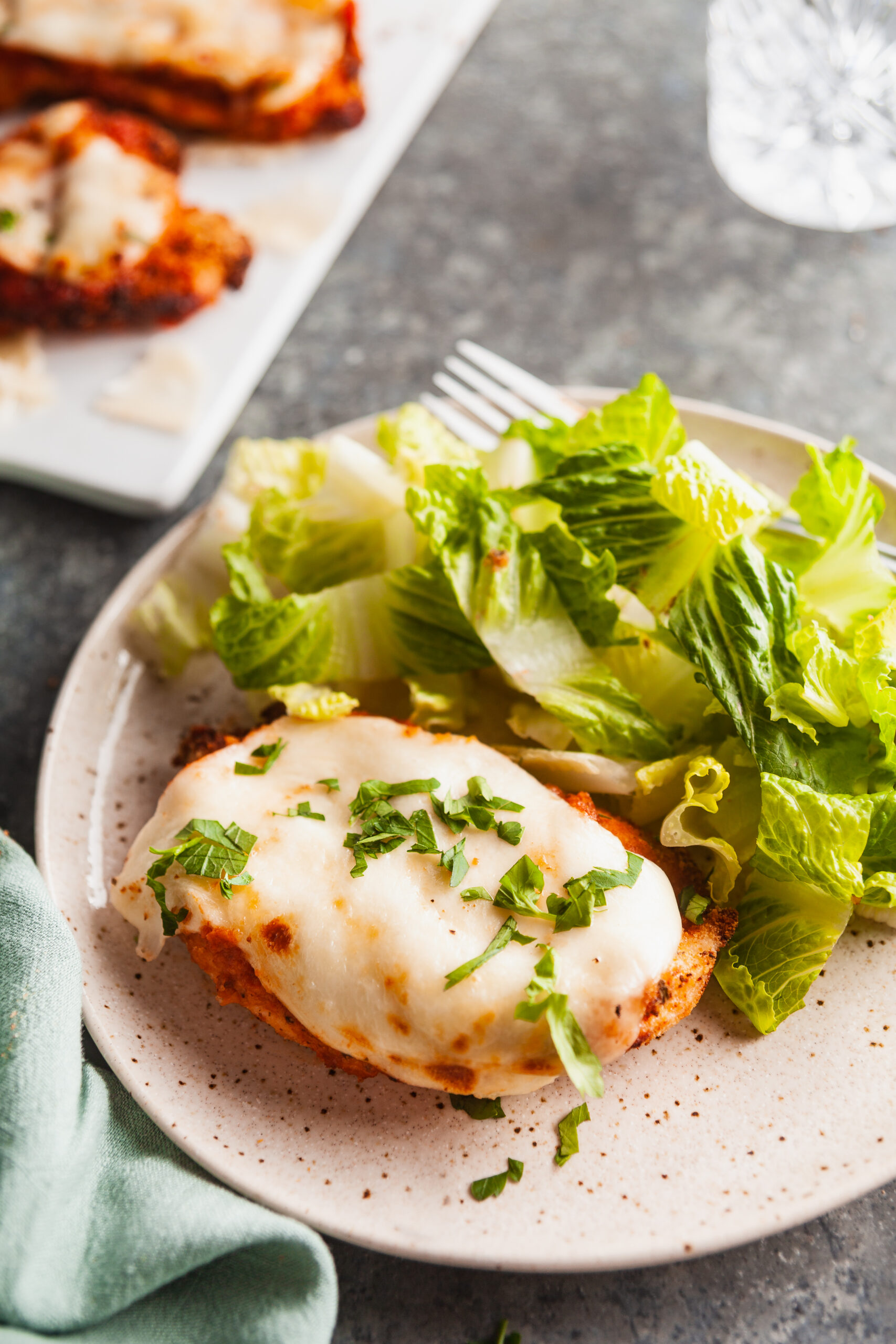 Air fryer chicken parmesan and green salad on a plate.
