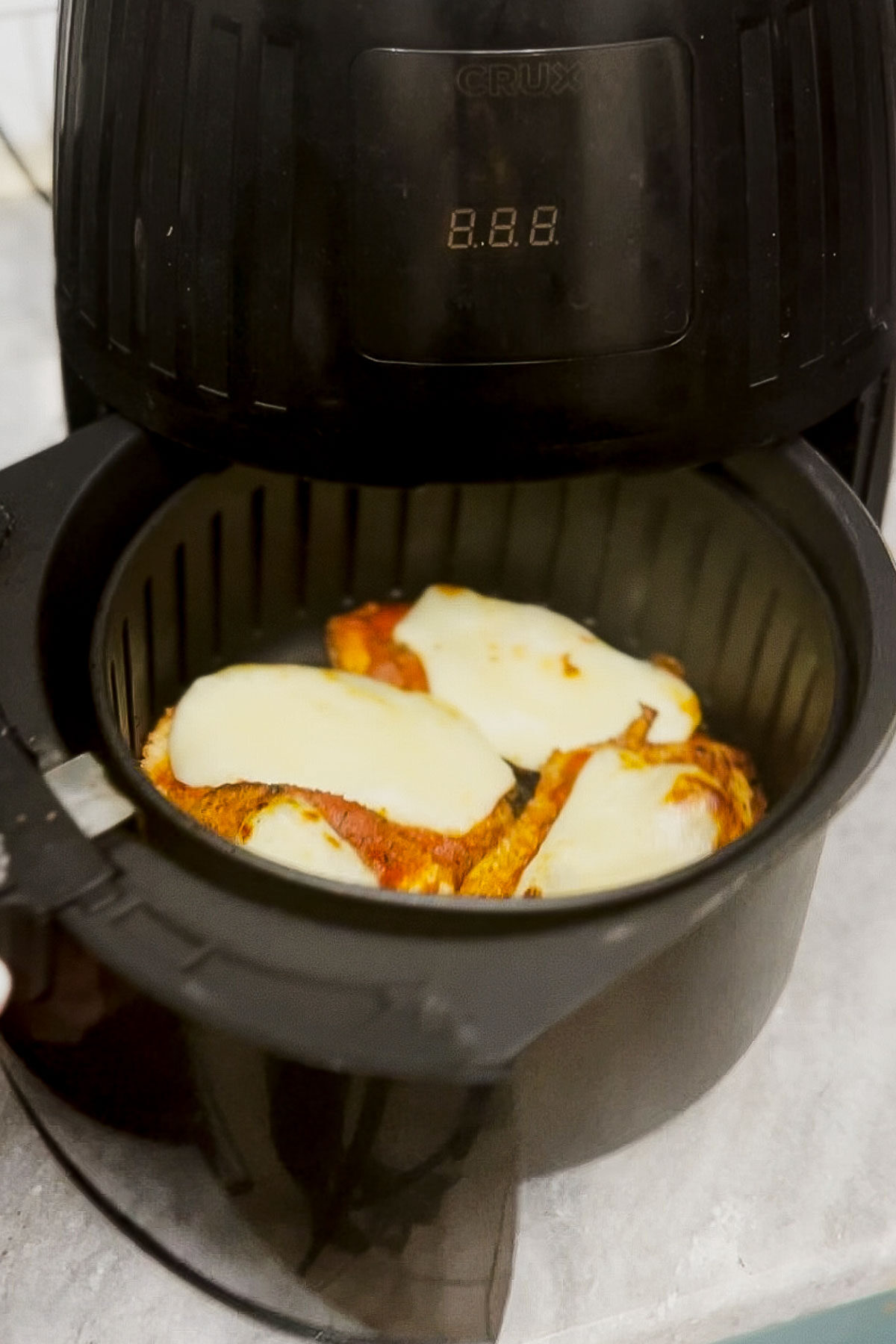 Chicken parmesan in an air fryer basket.