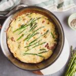 Overhead view of an asparagus frittata in a stainless skillet.