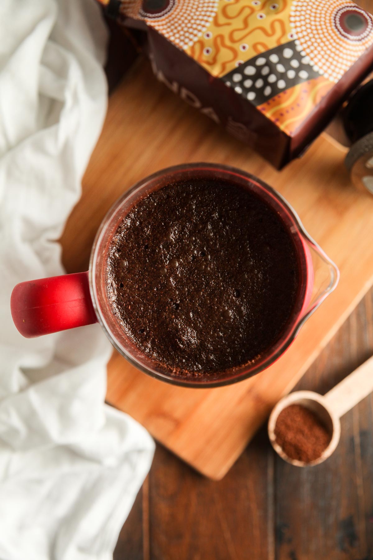 A french press filled with water and coffee grounds, after stirring. 