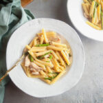 Landscape image of roasted garlic pasta in a white dish.