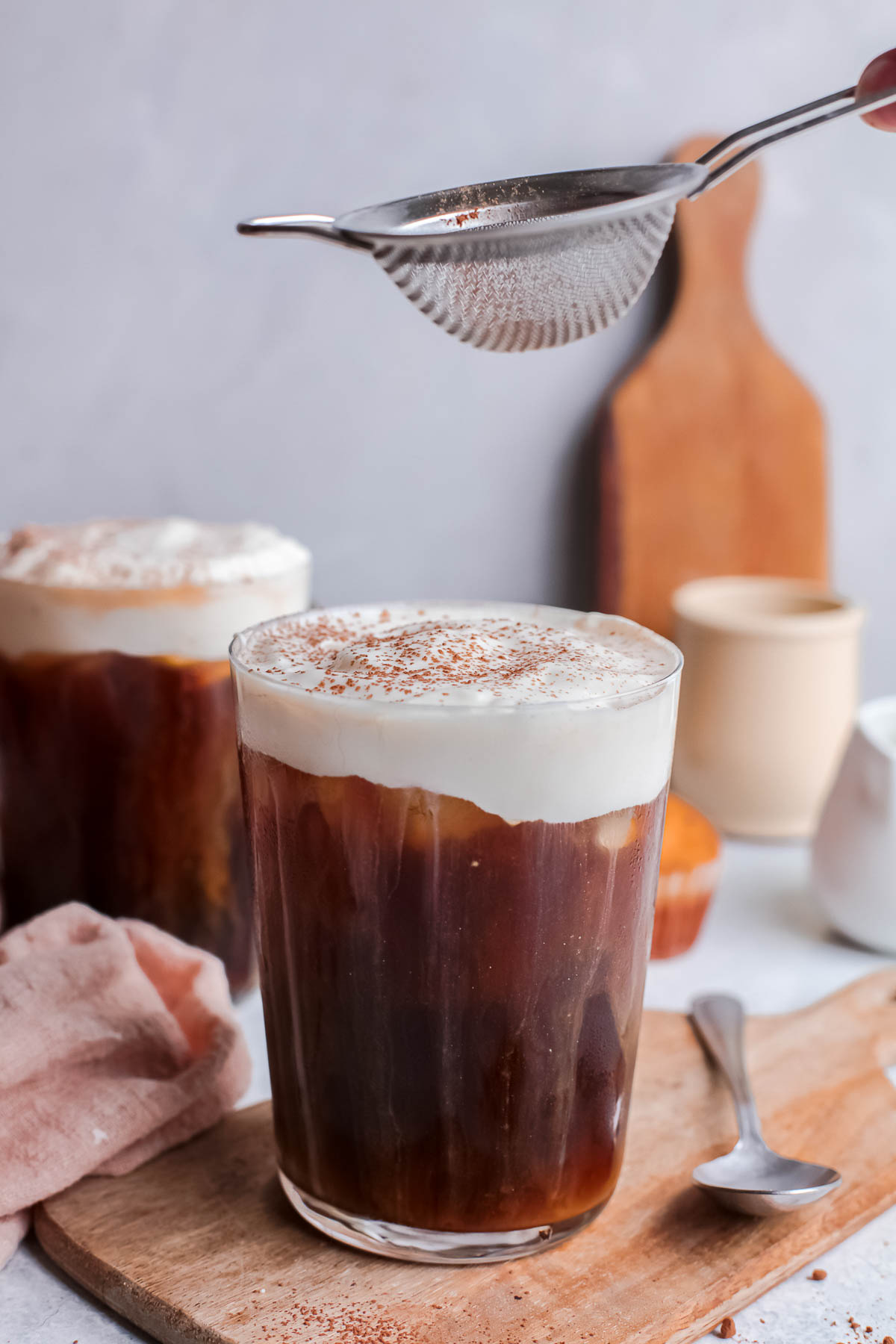 Dusting cocoa powder over a cold brew coffee. 
