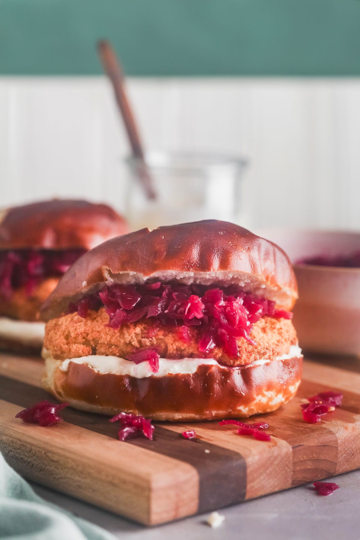 A chicken schnitzel sandwich with red cabbage and lemon sour cream sauce on a butcher block.