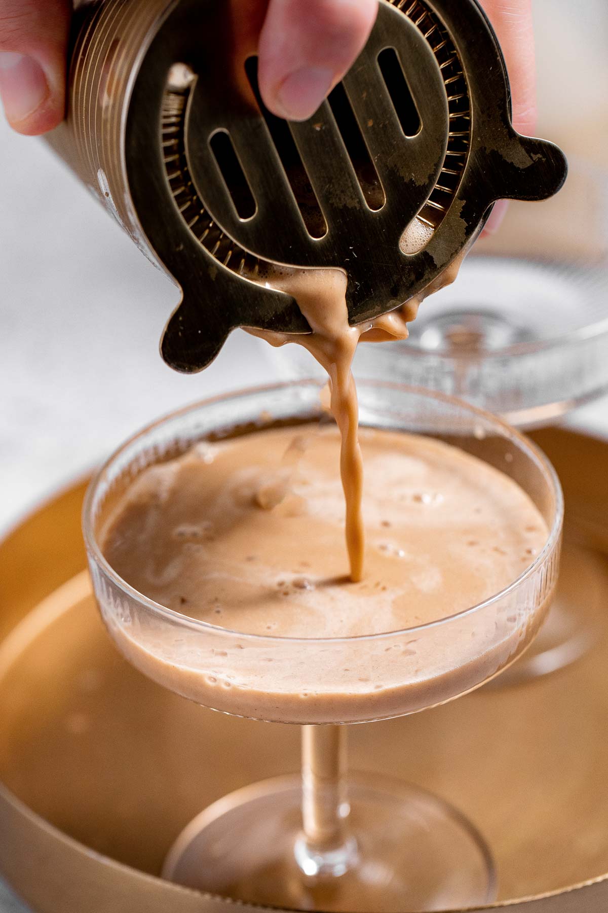 Pouring the martini into a chilled glass.