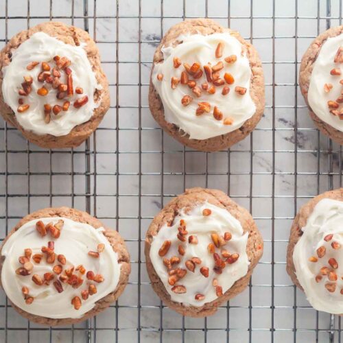 Frosted carrot cak cookies with pecans on a cooling rack.