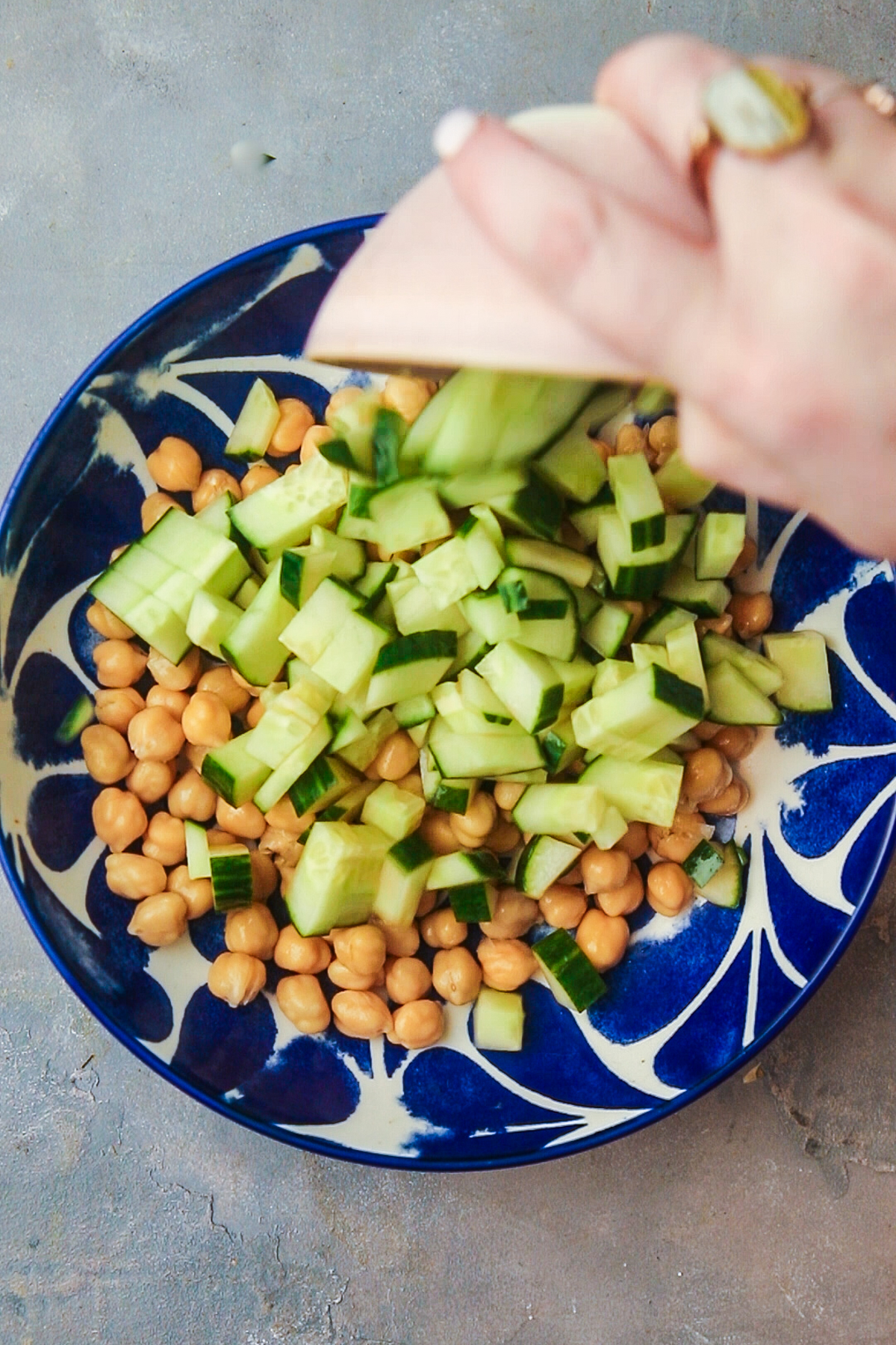 Adding diced cucumber to the chickpeas. 