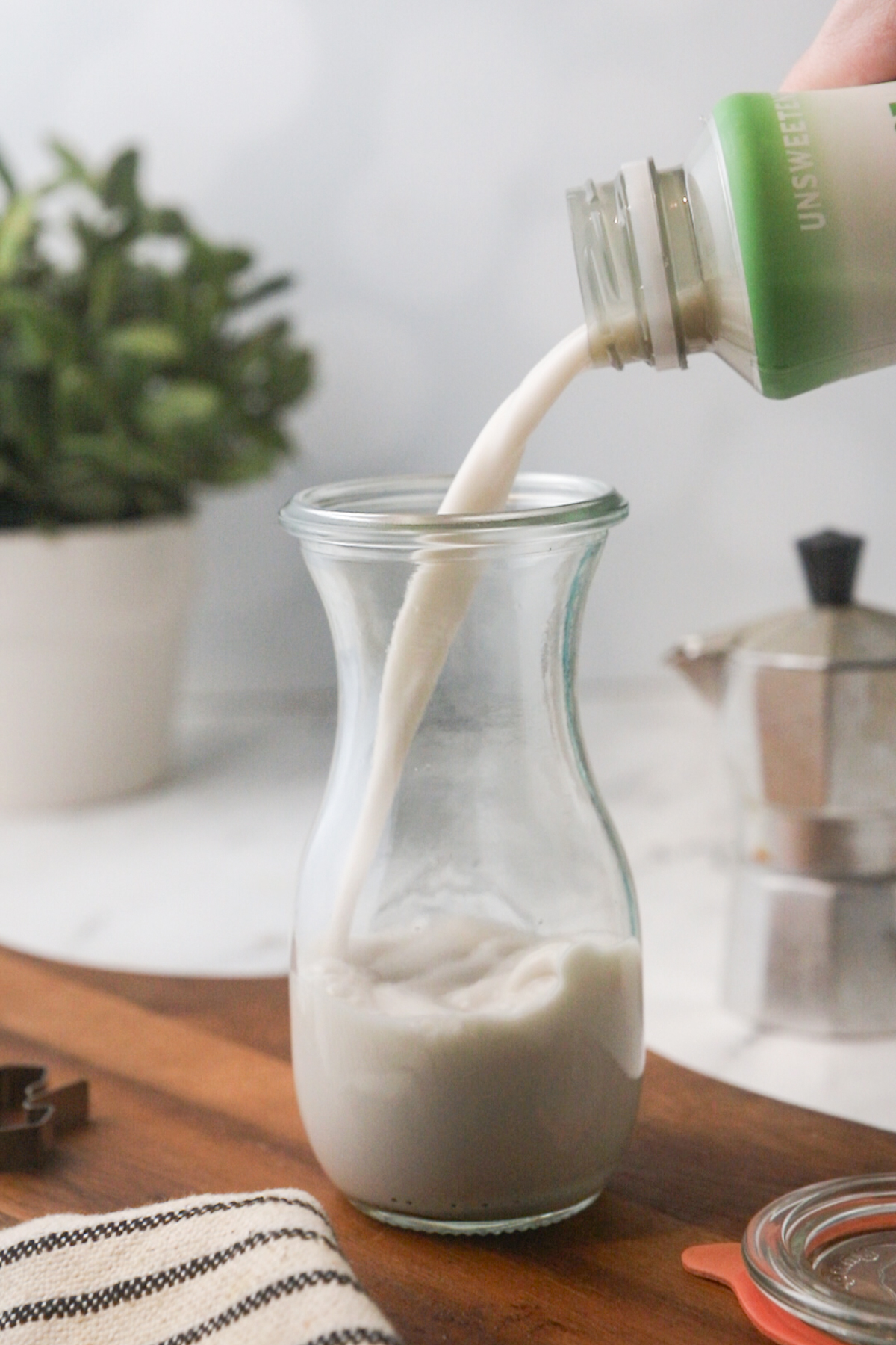 Pouring almond milk into a small carafe.