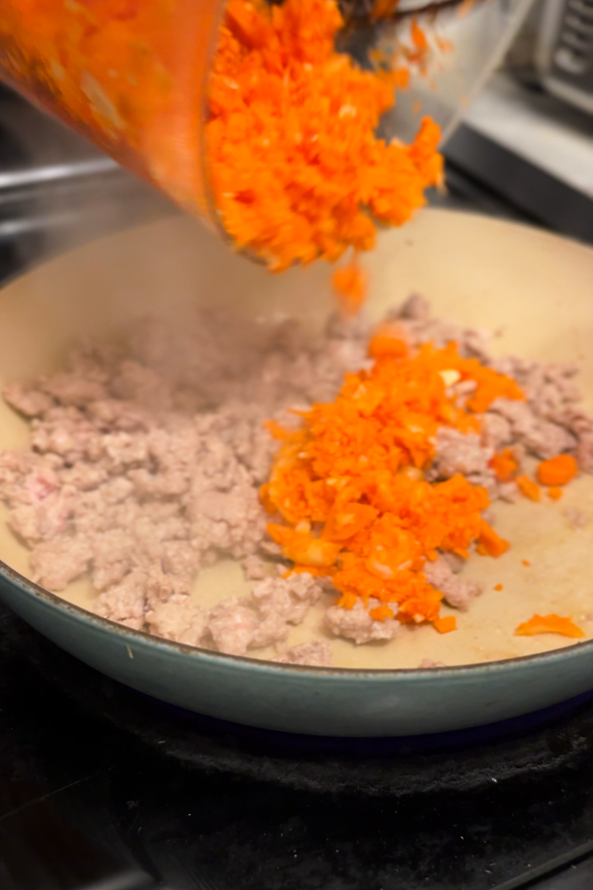 Adding chopped vegetables to the browned pork. 