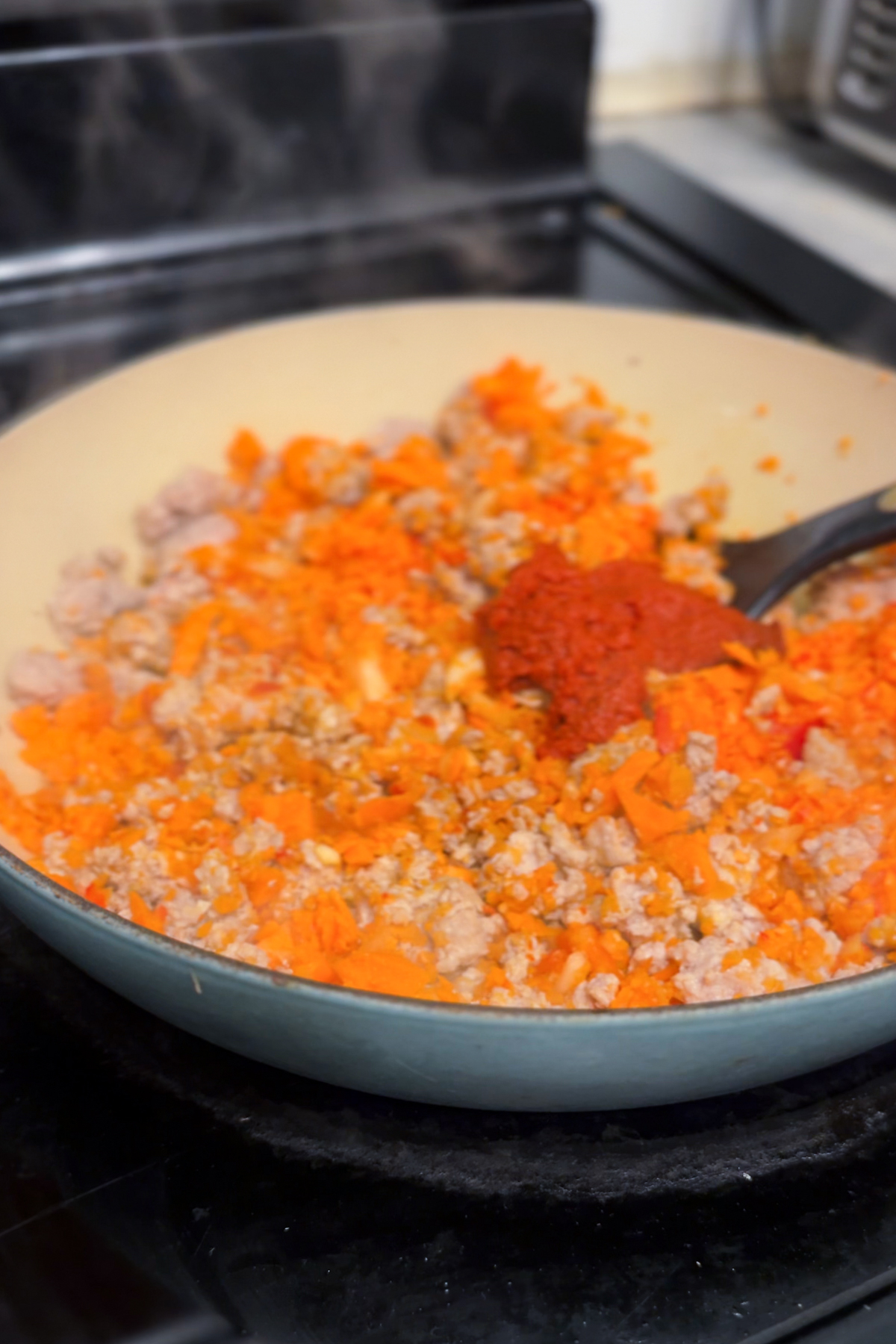 Stirring in red curry paste. 