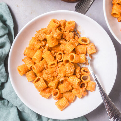 Overhead view of a white bowl full of creamy red curry rigatoni.