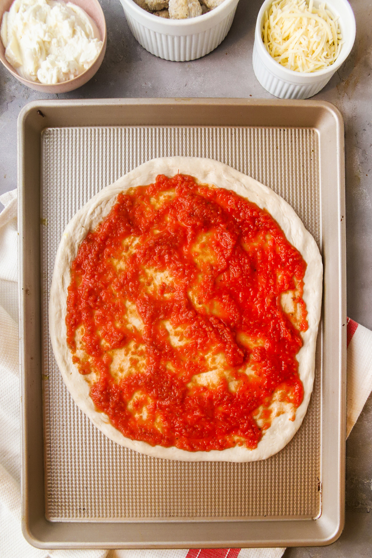 Spread sauce on the shaped dough, leaving a border aroudn the edge. 