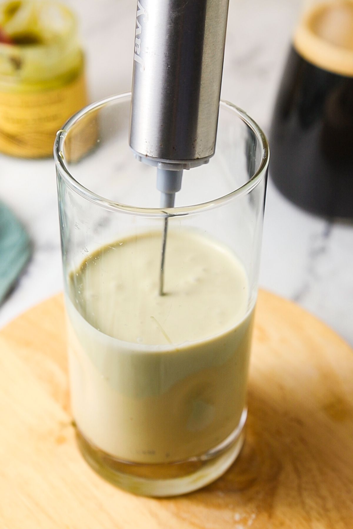 Blending pistachio cold foam with a handheld milk frother. 