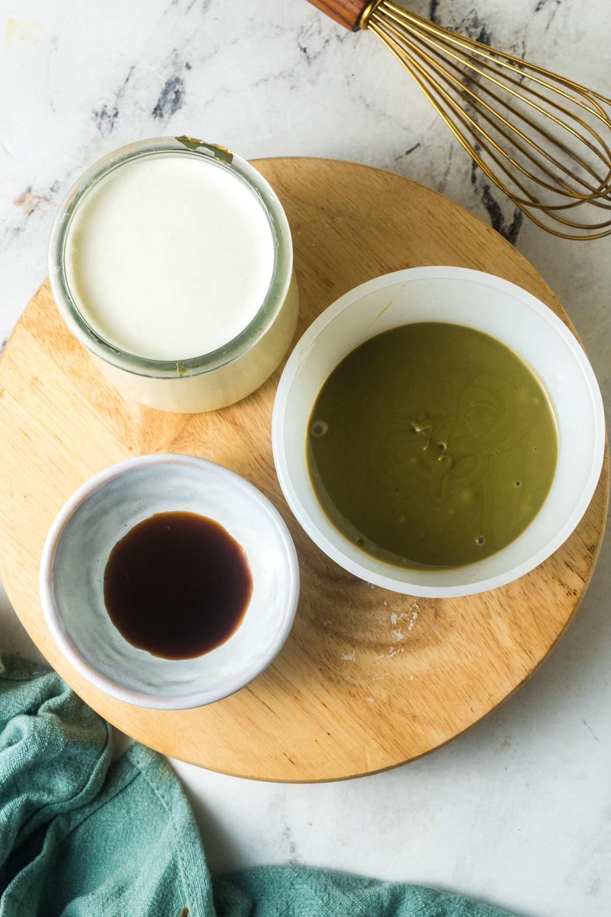 An overhead view of the ingrediencts needed to make pistachio cold foam sitting on a round cutting board. 