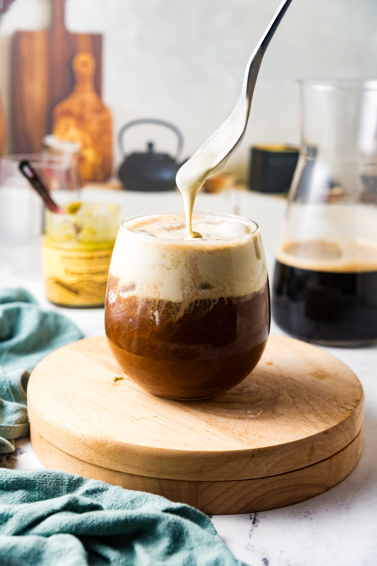 Spooning homemade pistachio whipped cream onto a cold brew coffee.