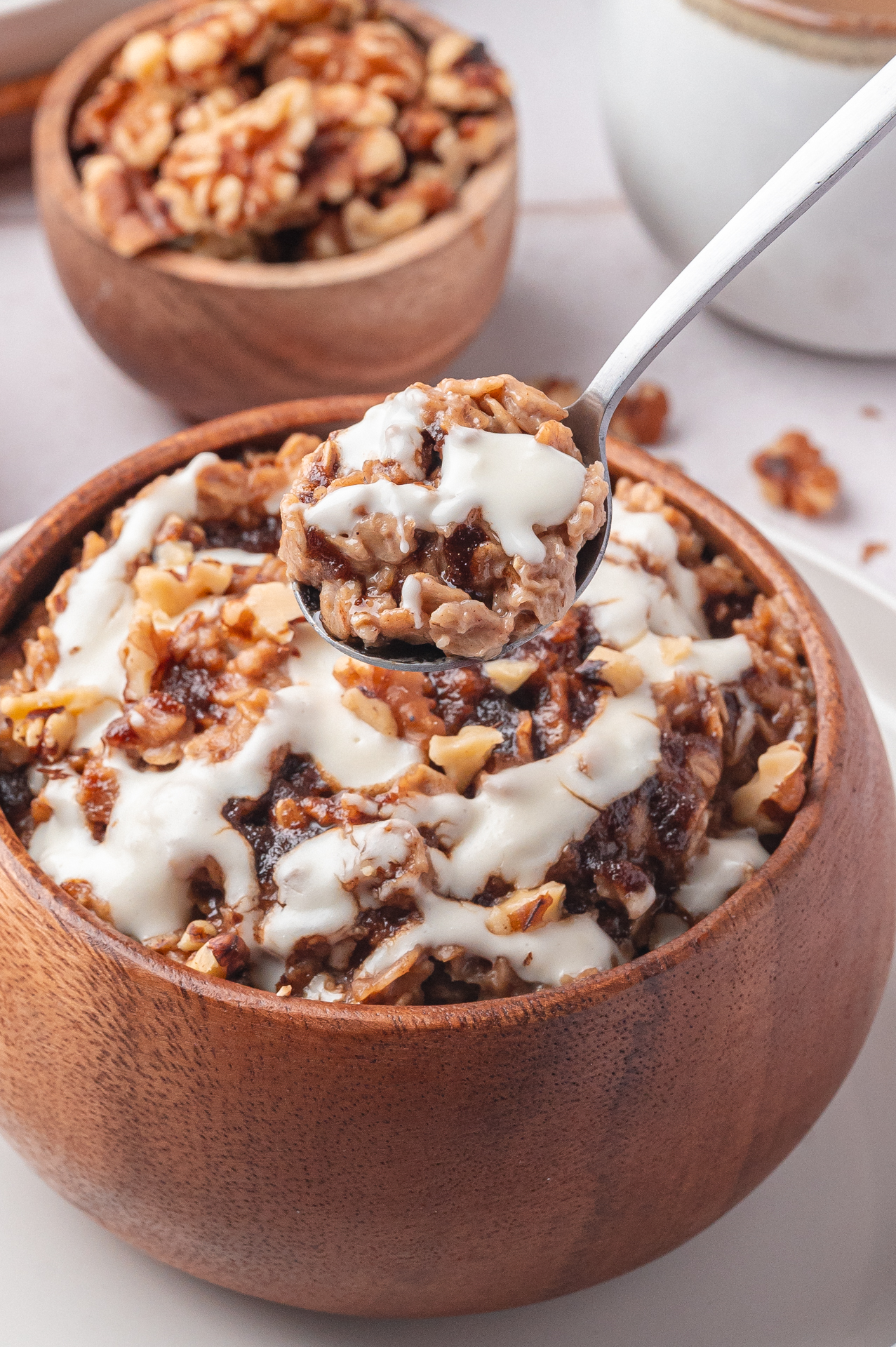 Taking a spoon from a bowl of cinnamon roll oatmeal swirled with cinnamon-sugar topping and cream cheese. 